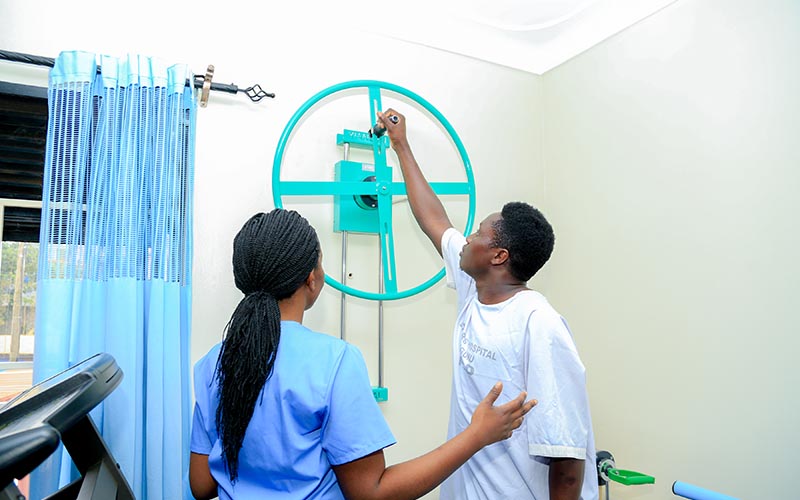 A clinician supporting a patient during rehabilitation at Doctors Hospital Sseguku